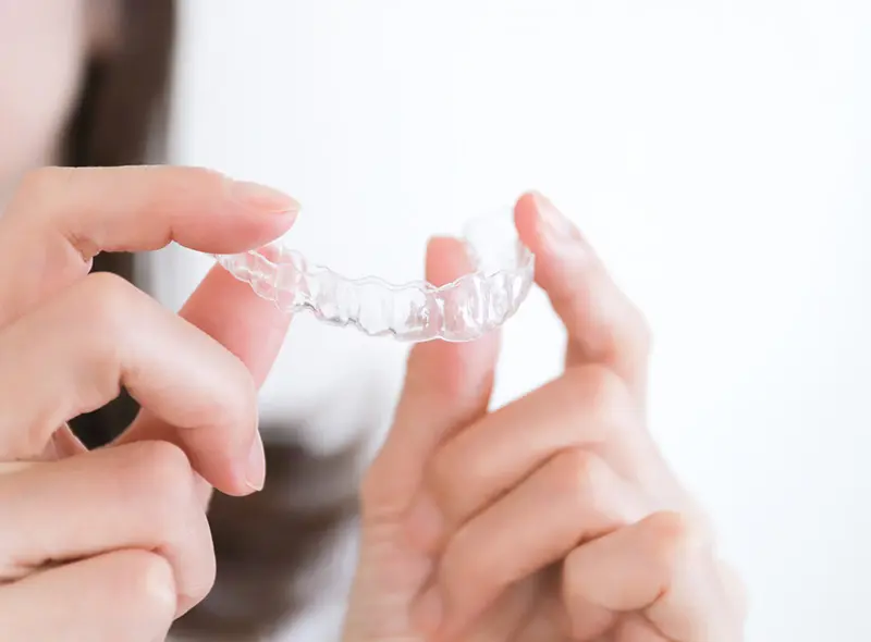 透明なマウスピースを持つ手