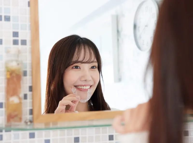 鏡の前でマウスピースを装着する女性